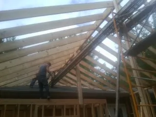 Rafters going up over a new addition with a worker on the wall in Covington