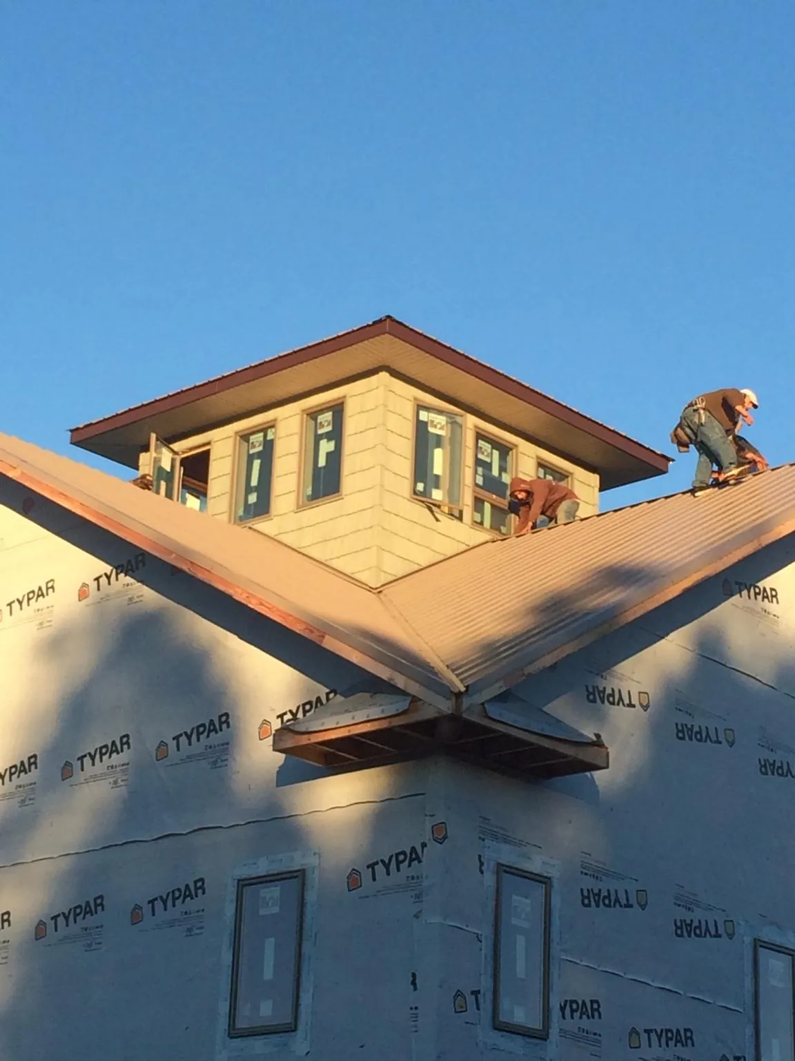 Roofers working around a rooftop cupola on a new metal roof at sunset — Roof Waterproofing in Covington by Roofing Brothers